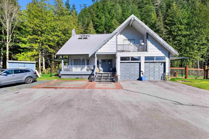 View of front of property featuring a porch, asphalt driveway, a garage, and a metal roof