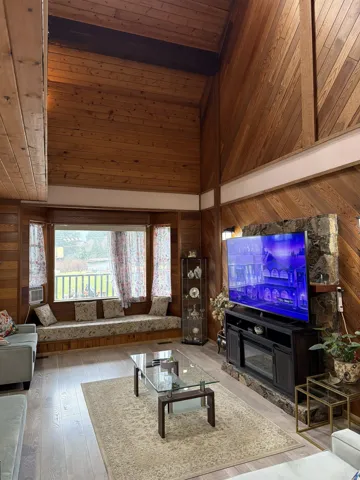 Living area featuring a vaulted wooden ceiling, hardwood / wood-style flooring, and wooden walls