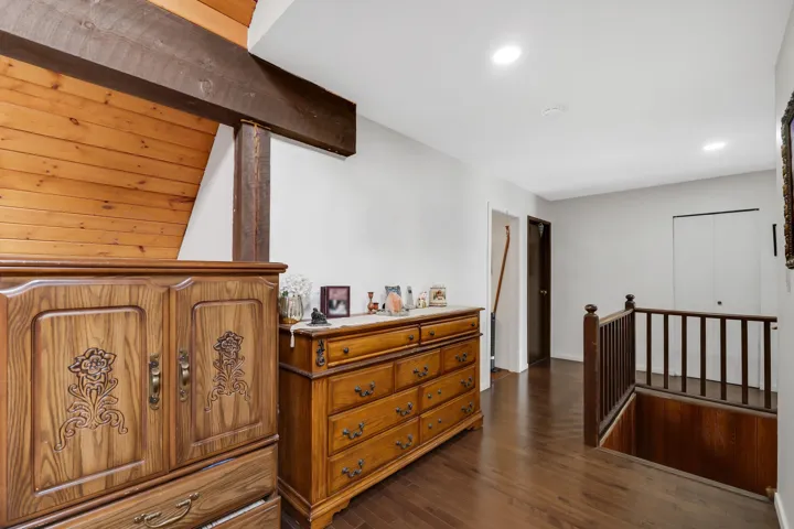 Hallway with an upstairs landing, dark wood-style floors, and recessed lighting