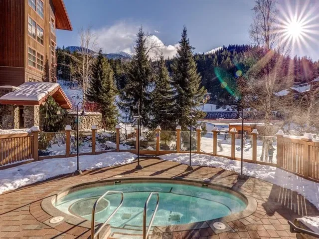 Snow covered pool with a hot tub and a mountain view