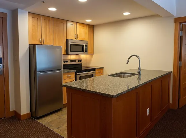 Kitchen with stainless steel appliances, a peninsula, dark stone counters, and recessed lighting