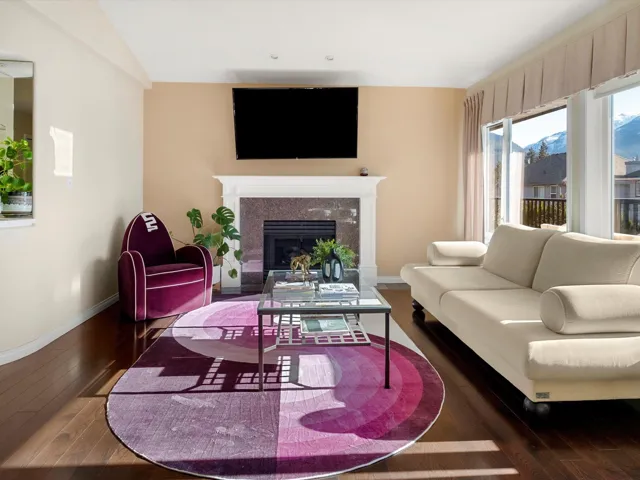Living area featuring a glass covered fireplace, vaulted ceiling, baseboards, and hardwood / wood-style floors