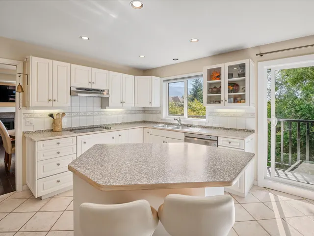 Kitchen featuring tasteful backsplash, glass insert cabinets, black electric stovetop, under cabinet range hood, and dishwasher