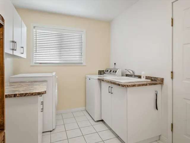 Laundry area featuring light tile patterned floors, baseboards, cabinet space, a sink, and washer and dryer
