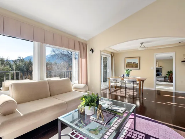 Living room featuring vaulted ceiling, hardwood / wood-style flooring, arched walkways, and baseboards