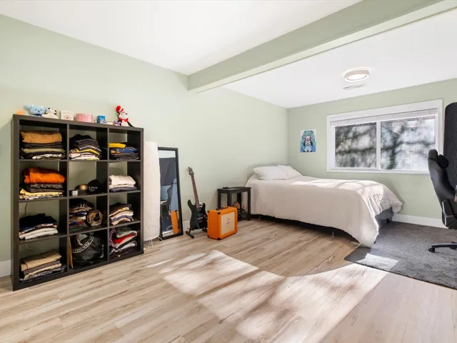 Bedroom with beam ceiling, baseboards, and wood finished floors