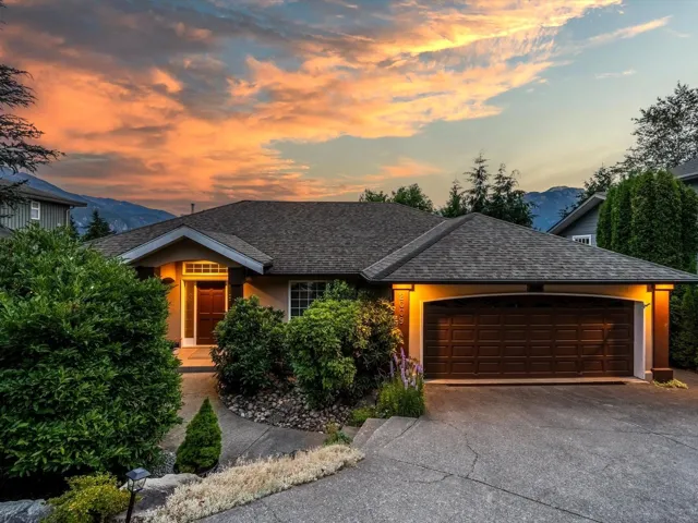 View of front of home featuring stucco siding, a mountain view, concrete driveway, a shingled roof, and a garage