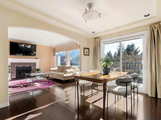 Dining room featuring arched walkways, a tiled fireplace, a tray ceiling, and wood-type flooring