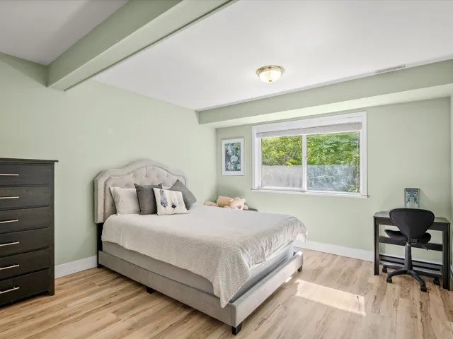 Bedroom featuring beam ceiling, baseboards, visible vents, and light wood finished floors
