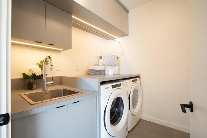 Laundry area with washing machine and dryer, baseboards, tile patterned floors, a sink, and cabinet space