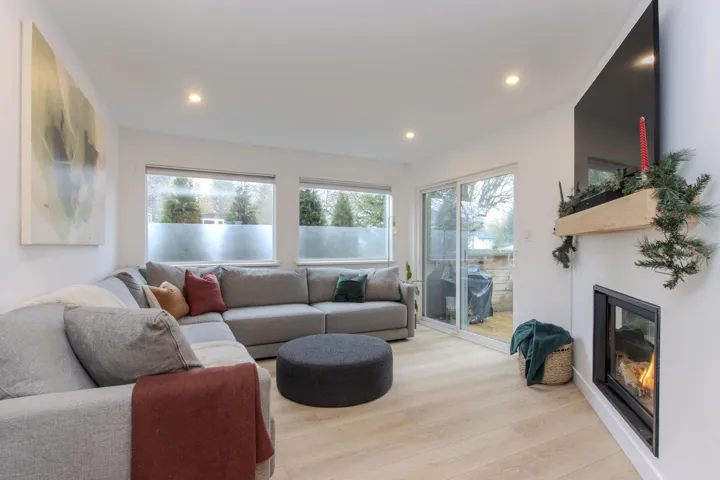 Living room featuring wood finished floors, a glass covered fireplace, healthy amount of natural light, and recessed lighting