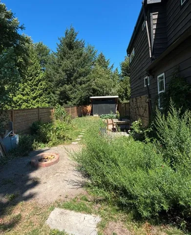 Fenced backyard featuring a fire pit and a storage unit