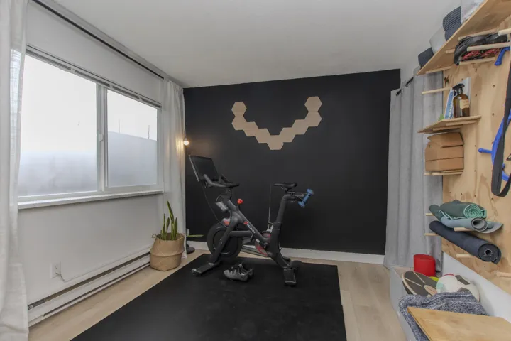 Exercise room with a baseboard heating unit, light wood-type flooring, and an accent wall