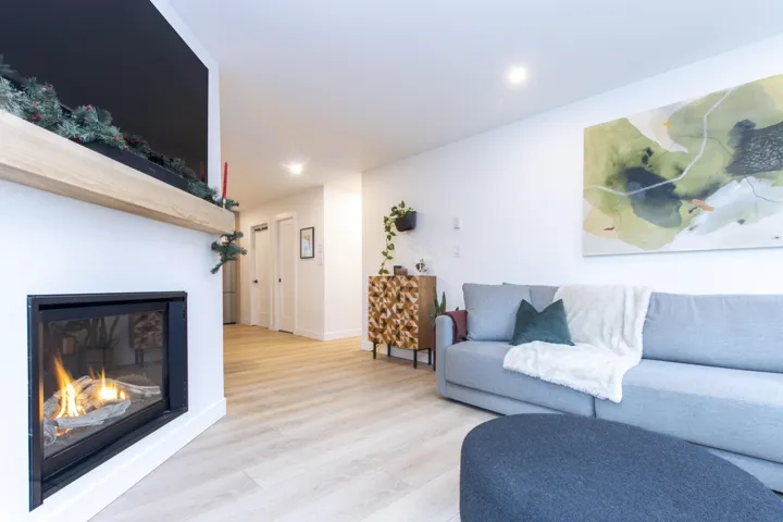 Living area featuring wood finished floors, a glass covered fireplace, and recessed lighting