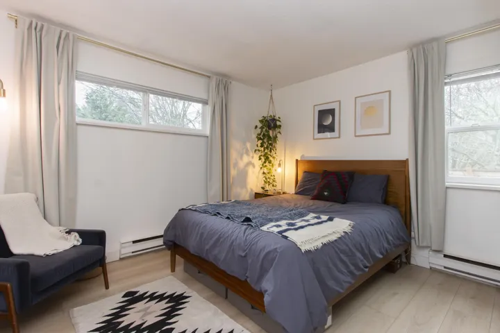 Bedroom with wood finished floors and a baseboard heating unit