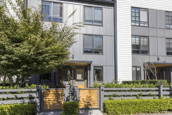 Modern multi-level exterior with panel siding and a wood-slatted fence