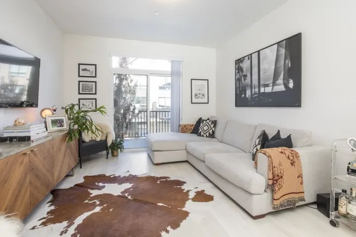 Recessed lighting, light wood-finish flooring, and a sliding glass door to a private balcony with metal railings