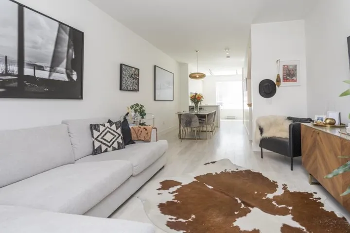 Open-concept living space featuring light wood-finish flooring, recessed lighting, and a contemporary pendant light fixture