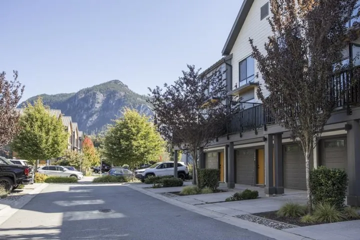 Contemporary townhome exterior with multiple garages, private balconies, and landscaped front yards