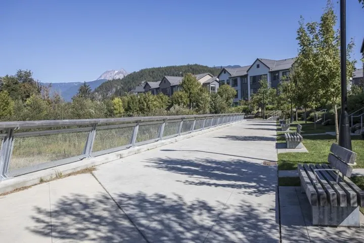 Concrete pedestrian pathway paralleled by a metal and wood-finish railing