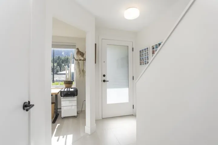 Light-toned flooring, white interior walls, and a frosted glass-paneled entry door with matte black hardware