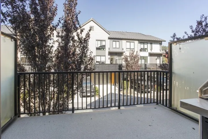 Balcony with a textured surface, black metal railing, and frosted glass privacy panels