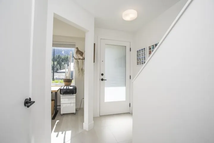 White interior door with frosted glass panel, recessed ceiling light, and light-toned floor tile