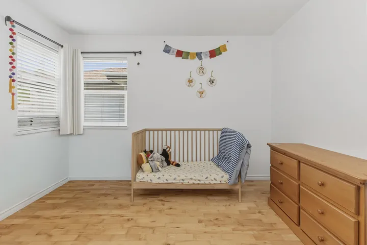 Bright room featuring wood-finish flooring, white walls, and two windows with blinds