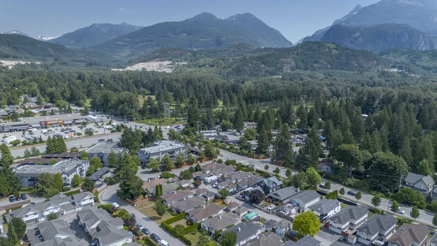 Residential community with a variety of housing styles, abundant mature trees, and mountainous terrain in the background