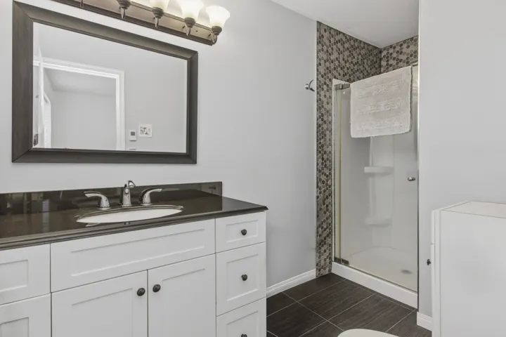Bathroom featuring a white vanity with dark hardware, a dark stone countertop, and an undermount sink