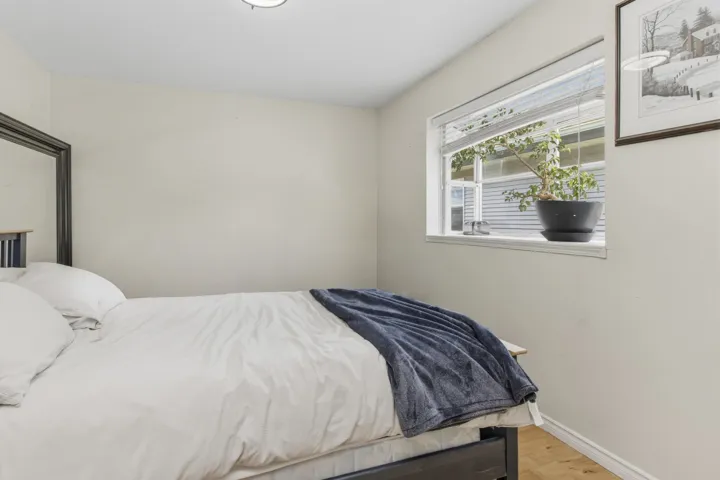 Room featuring light-toned walls, wood-finish flooring, and a window with blinds