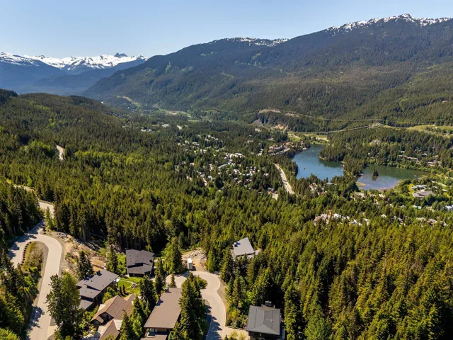 Drone / aerial view of a heavily wooded area and a water and mountain view