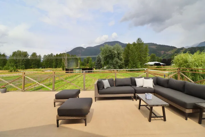 Expansive outdoor patio featuring a concrete surface, wooden perimeter fencing, and distant mountain backdrops