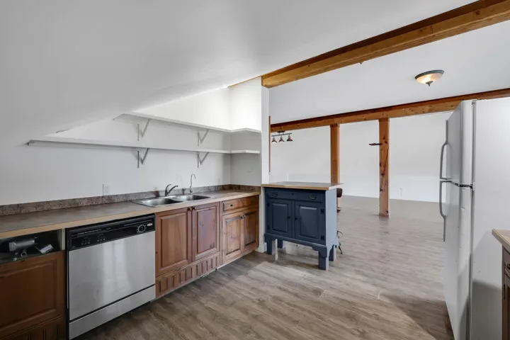 Kitchen with open shelves, freestanding refrigerator, dishwasher, light wood finished floors, and light countertops