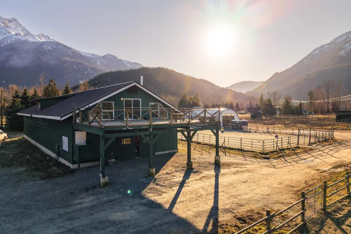 Back of property with an outbuilding, a deck with mountain view, an exterior structure, and a rural view