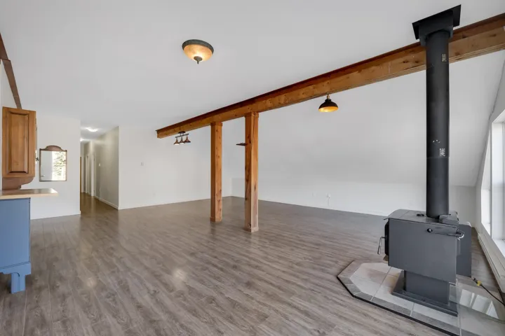 Unfurnished living room with dark wood-style flooring and a wood stove