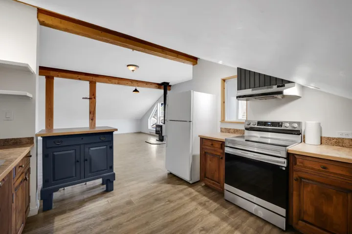 Kitchen featuring stainless steel electric range oven, freestanding refrigerator, vaulted ceiling with beams, open shelves, and light wood-style floors