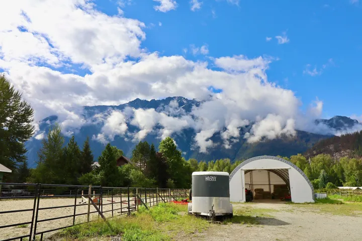 Mountain backdrop framing a property featuring a large open-front arch-style building