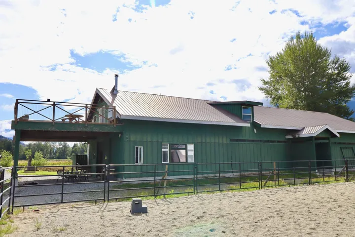 Two-story green-sided structure with a metal roof and an elevated deck