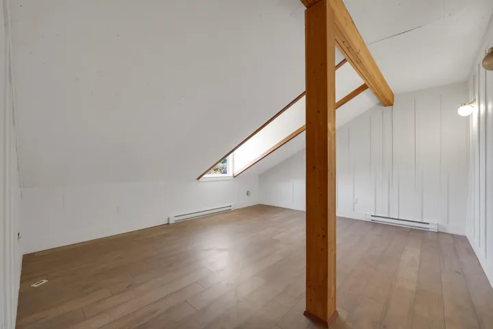 Bonus room with vaulted ceiling with beams, baseboard heating, light wood-style floors, and a skylight