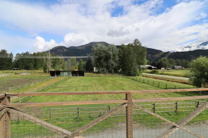 Expansive fenced pastureland with mountain backdrop