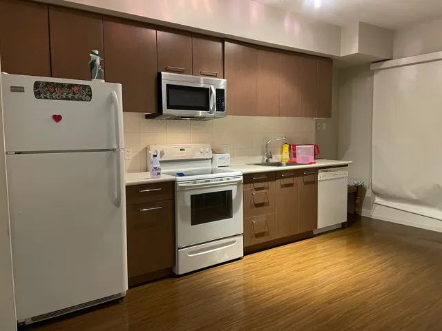 Kitchen with white appliances, dark wood-style floors, light countertops, and tasteful backsplash