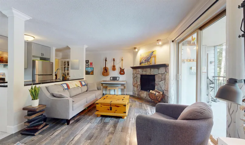 Living area featuring wood finished floors, a textured ceiling, a fireplace, ornamental molding, and baseboards