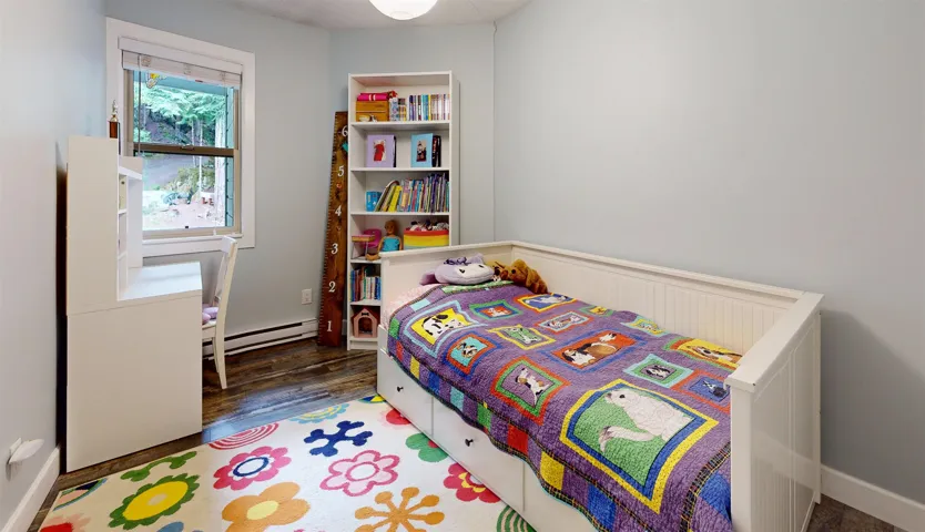 Bedroom with a baseboard radiator, wood finished floors, and baseboards
