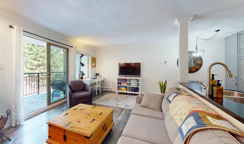 Living room with wood finished floors, baseboard heating, a textured ceiling, and decorative columns