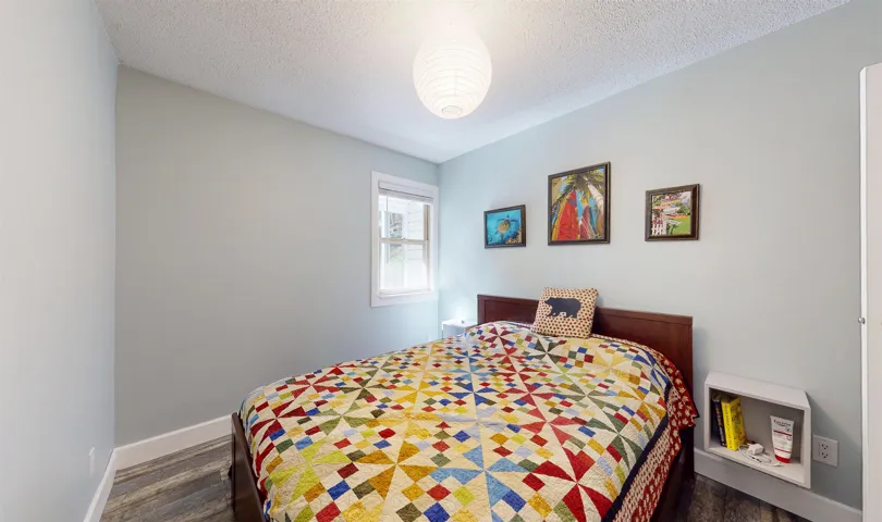 Bedroom featuring dark wood-style floors, a textured ceiling, and baseboards