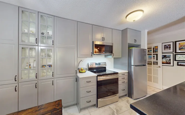 Kitchen featuring appliances with stainless steel finishes, gray cabinets, a textured ceiling, and glass insert cabinets