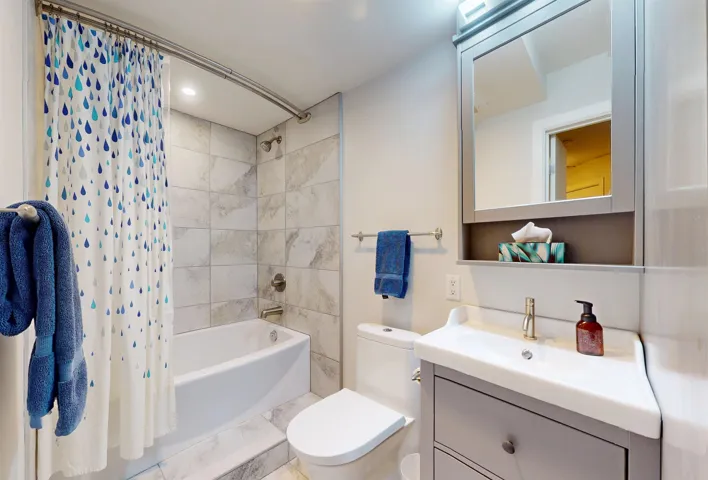 Full bath with shower / bathtub combination with curtain, vanity, and toilet