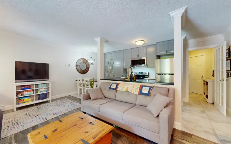 Living area featuring ornamental molding, ornate columns, baseboards, and a textured ceiling