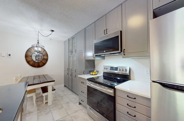 Kitchen featuring stainless steel appliances, light marble finish flooring, gray cabinets, light countertops, and a textured ceiling